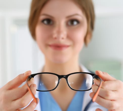 image of an optometrist holding out a pair of glasses that were bought because of great vision insurance coverage in Franklin, TN